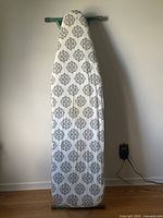 Ironing board standing upright, cover visible