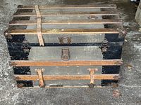 Front view of wood slat canvas steamer trunk with leather straps and metal hardware