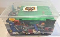Full view of clear bin filled with Lego pieces, lid closed