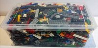 Plastic lidded bin filled with assorted Lego pieces, top view