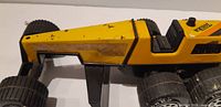 Side view of yellow pressed steel Tonka grader body, wheels and paint wear