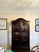 Front view of closed china cabinet showing glass doors, arched crown, brass hardware