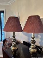 Front view of both lamps on tabletop showing gold-tone bases and burgundy shades