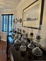 Full group of oil lamps lined on dark furniture