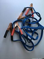Coiled blue booster cables with four clamps visible