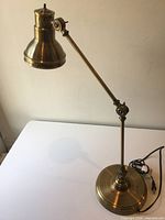 Full view of brass-tone desk lamp on table