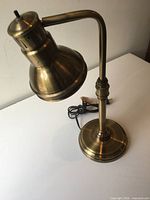 Full view of brass-tone metal desk lamp showing shape and cord
