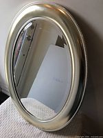 front view of oval mirror with grey painted beaded frame