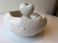 Front view of white ceramic fountain showing cat face detail and heart spout