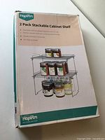 Front of box showing product name, brand and image of two stacked shelves with jars
