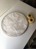 Folded stack of white paper lanterns beside two stacks of yellow wax fuel rings