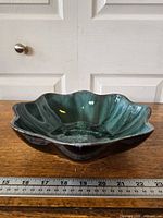 Oblique view of teal drip glaze scalloped dish showing exterior and interior
