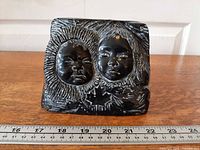 Front view showing two Inuit faces and maple leaf, ruler for scale