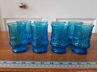 Front view of eight laser blue Rain Flower tumblers aligned