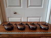 four lidded stoneware crocks front view with ruler