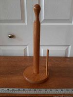 Front view of oak paper towel holder showing spindle, side dowel and base