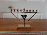 Front view of modernist Karshi menorah showing nine candle holders and triangular motif