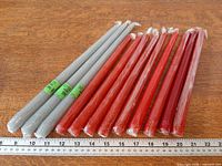 Group of twelve shrink-wrapped taper candles with ruler for scale