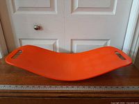 Full view of orange Simply Fit Board on wooden surface