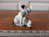 Front view of porcelain terrier family figurine beside ruler for scale