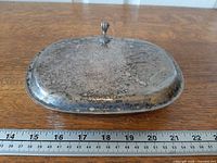 Top view of closed silent butler showing finial and tarnished plating with ruler for scale
