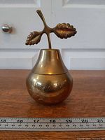 Front view of brass pear trinket box showing engraving and ruler for scale