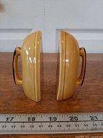 Side profile of both yellow ceramic shakers showing handle detail and glaze