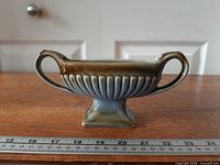 side view showing twin handles, fluted body, glaze colors and foot, ruler for scale