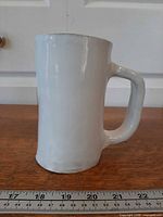 Side view of white stoneware stein showing full height and handle