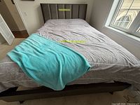 Top view of queen bed showing headboard, mattress, bedding with turquoise throw