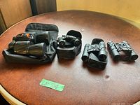 Four binoculars lined up with cases visible