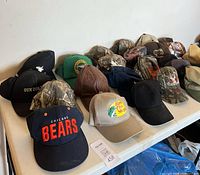 Tabletop view of multiple baseball caps including Chicago Bears and Bass Pro Shops hats