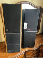 Front view of all four speakers showing brands and grille condition