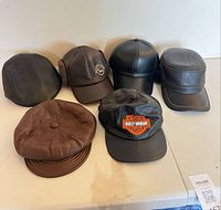 Six leather hats laid out showing fronts and tops