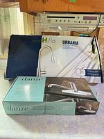 Sealed boxes of H2flo Urbania faucet and Danze faucet on countertop