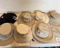 Seven Tilley hats laid out on table