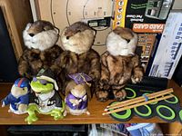 Group shot of three otter toys, three small plush figures, electronic drum pad with sticks