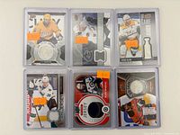 Front view of six Upper Deck Game Jersey cards in sleeves showing player images and jersey swatches