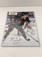 Front view of signed 8x10 Mathieu Joseph photo showing signature, authenticity sticker and protective sleeve