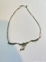 Full view of necklace laid flat showing chain style, turquoise cabochons and fringe drops