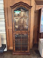 Front view showing entire glass front curio cabinet, two doors, arch top, veneer finish