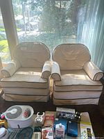 Pair of matching beige upholstered armchairs positioned side by side