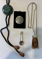 Group view: pendant necklace, pewter brooch, spoon pin, bolo tie