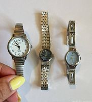 Three watches laid side by side showing dials and bracelets