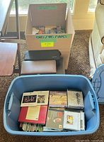 Overview of blue tote with CDs, cassette tapes, two CD wallets and box of media
