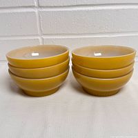 Six identical yellow Fire-King bowls stacked in two piles