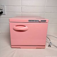 Front view of closed pink towel warmer showing control panel and power cord