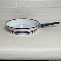 Side view of enamel frying pan showing handle and stripe design