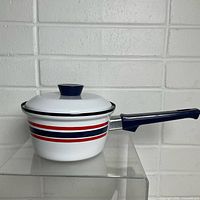 Side view of sauce pan with lid on, showing Celebration stripe pattern and handle