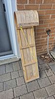 Full view of wooden toboggan standing upright against wall